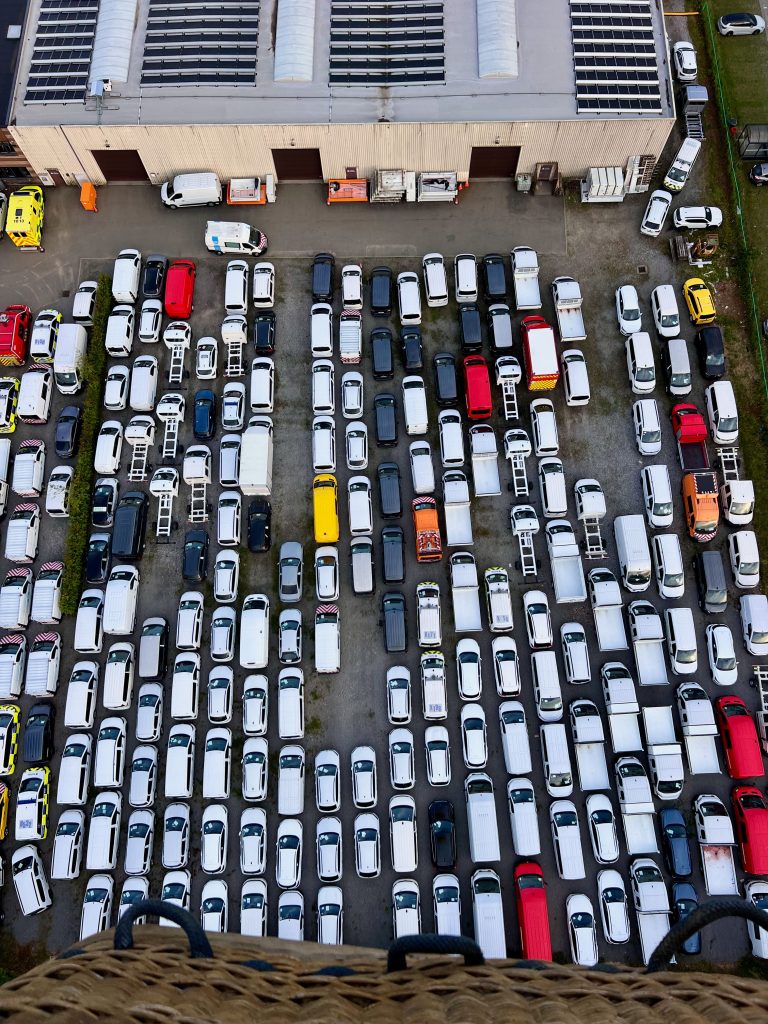 Vehicle Services Top view of an organized parking lot filled with multiple vehicles of various colors.